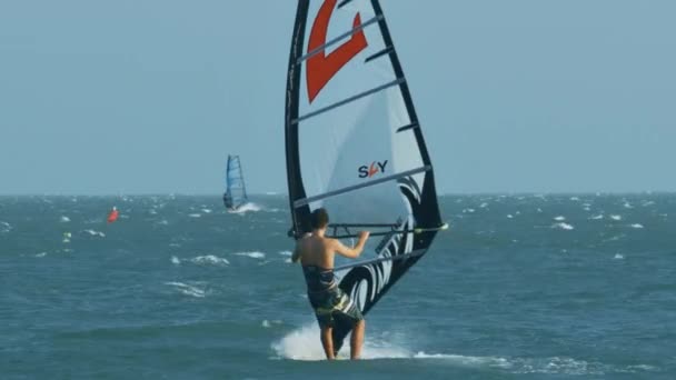 裸のトランクを持つ男 Windsurfs 嵐の海の波のカラフルなサーフボードの裏面表示を閉じる — ストック動画