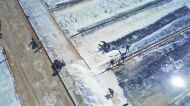 Panorama çalışkan insanlar beyaz tuz sahada güneş ışınlarının yansıması karşı özel araçlarla toplamak