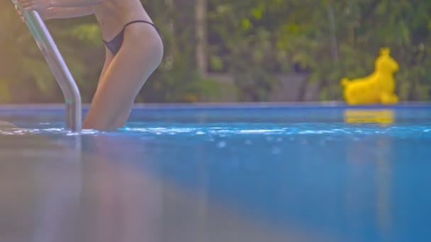 Slim loira menina mergulha na piscina contra plantas verdes Closeup — Vídeo de Stock