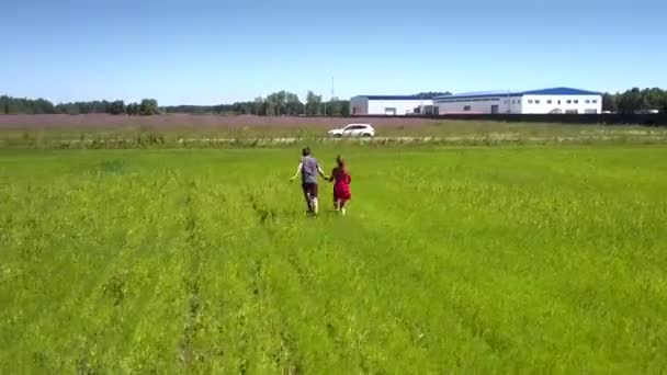 Ung man och vacker flicka springa tillsammans till fältet kanten — Stockvideo