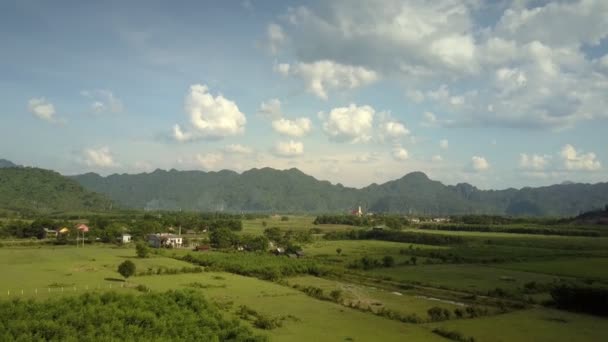 Green fields at town against mountains under sky aerial view — Stock Video