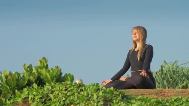 Uzun, dalgalı saçlı bayan yoga pozunda meditasyon yapıyor. — Stok video
