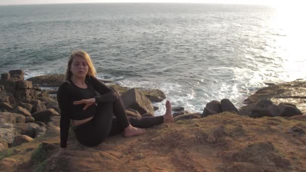 Jolie fille en survêtement noir se trouve sur la falaise rocheuse grise — Video