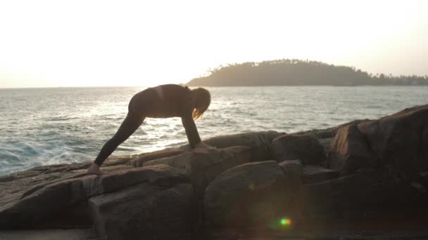 Silueta chica practica ejercicios de yoga de pie sobre roca — Vídeos de Stock