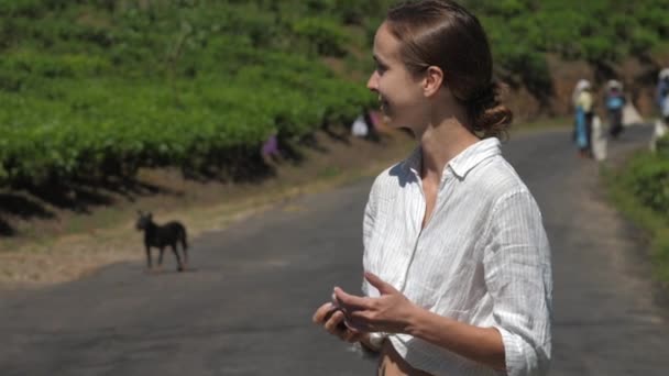 Женщина в рубашке делает фотографии рабочих на чайных плантациях — стоковое видео