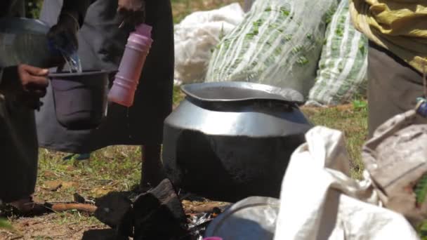 Senhora local prepara chá em panela de metal grande na fogueira — Vídeo de Stock