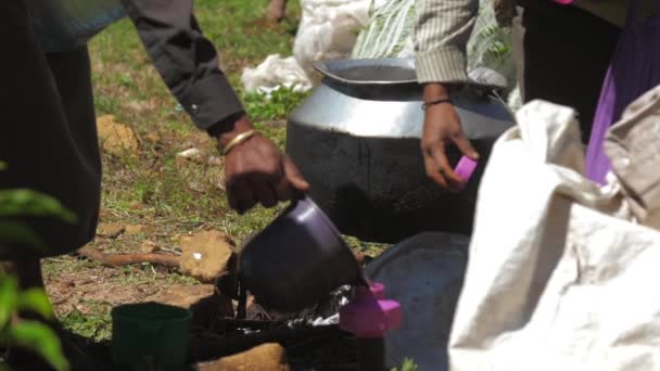 Señora local prepara té en una olla grande de metal en la hoguera — Vídeo de stock