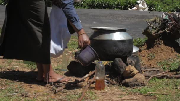 Dame schenkt zwarte thee uit metalen pot in plastic fles — Stockvideo