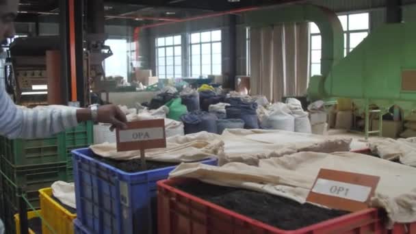 Trabalhadores em macacões especiais filtram folhas de chá na máquina — Vídeo de Stock