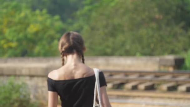 Joven mujer camina a la carretera ferroviaria entre la naturaleza cámara lenta — Vídeos de Stock