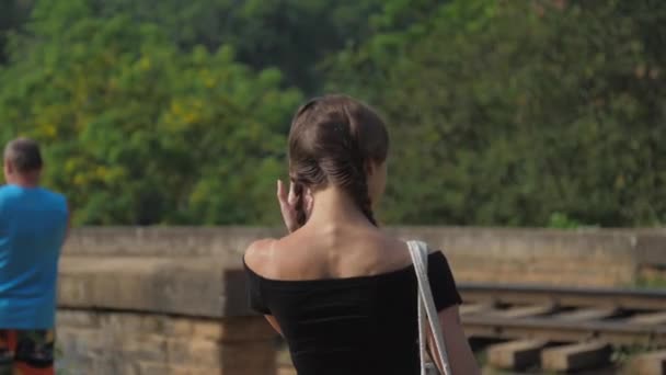 Chica camina a la vieja carretera ferroviaria entre la naturaleza cámara lenta — Vídeo de stock