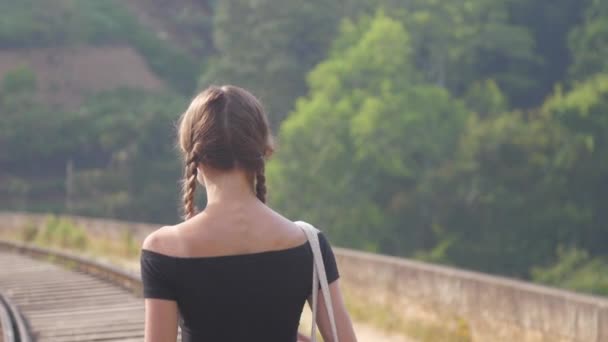 Fille en noir haut promenades à chemin de fer parmi la nature gros plan — Video