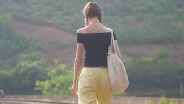Menina com tranças caminha para a velha estrada de ferro entre a selva — Vídeo de Stock