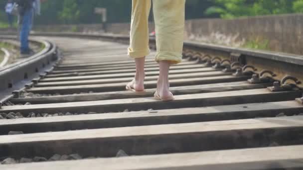 Vrouw loopt op dwarsliggers langs spoor verleden reizigers — Stockvideo