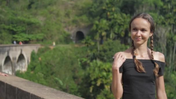 Meisje zit op beroemde brug en geniet van wilde tropische natuur — Stockvideo