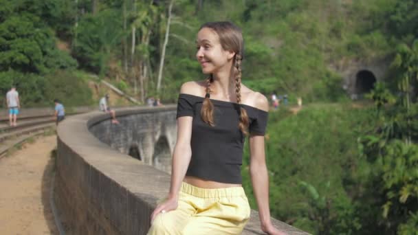 Vrouw zit op historische brug tegen wild landschap — Stockvideo