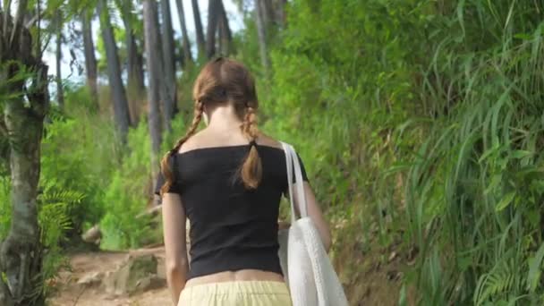 Slim girl walks along highland path surrounded by trees — 비디오