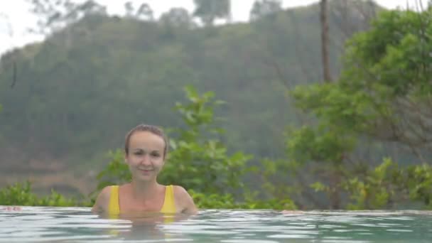 Красива дівчина в жовтому зверху посміхається з краю басейну — стокове відео