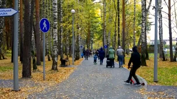 Arkaya bakan genç, park yolunda kırmızı scooter sürüyor. — Stok video