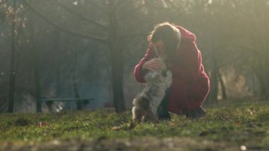 woman in coat pets funny shitzu dog and feeds animal