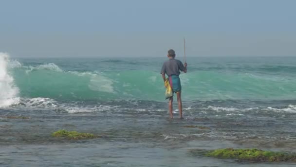 Gerijpte Sinhalese man staat in eindeloos blauw zeewater met staaf — Stockvideo