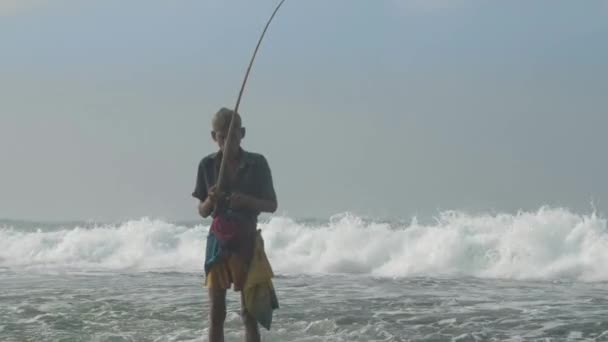 Vecchio uomo singalese con canna da pesca in legno a oceano lento — Video Stock