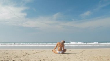 Avrupalı kız deniz kıyısında yoga yapıyor.