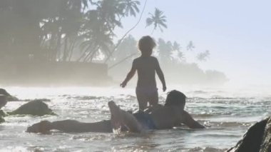 Baba ve kızı deniz kıyısında birlikte oynuyorlar.