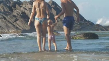 Anne, baba ve kızın aileleri deniz kıyısında birlikte oynuyorlar.