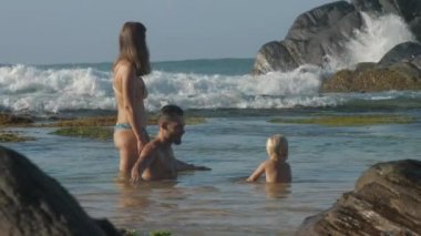 Anne, baba ve kızın aileleri deniz kıyısında birlikte oynuyorlar.