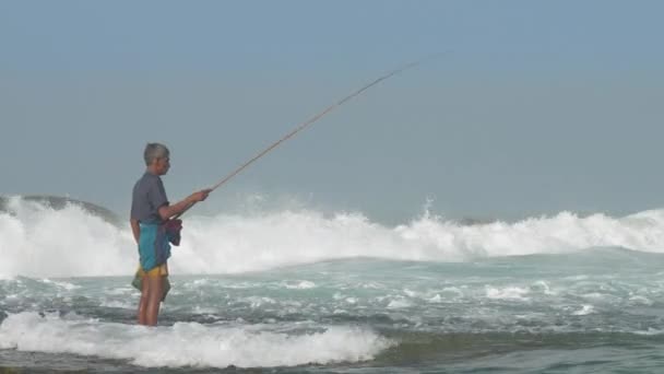 Starý rybář kontroluje dřevěný rybářský prut ve vodě — Stock video