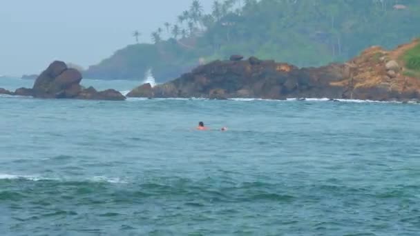 Femme attrape vague debout sur planche de surf contre paysage — Video