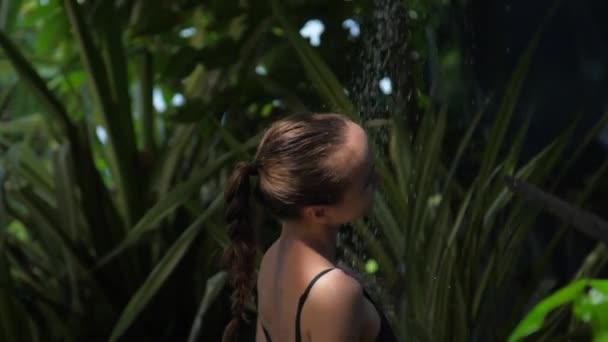 Mujer toma ducha relajante contra las plantas tropicales verdes — Vídeo de stock