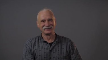 Stüdyoda akıllı telefon gösteren Avrupalı olgun bir adam karanlık arka planda izole edilmiş.