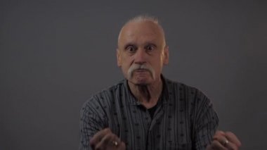 Stüdyoda yumruğunu gösteren Avrupalı olgun bir adam koyu arka planda izole edilmiş.