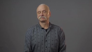 Stüdyoda şüpheli yüz ifadesi olan Avrupalı olgun bir adam koyu arka planda izole edilmiş.