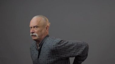 Stüdyoda sırtı ağrıyan Avrupalı olgun bir adam karanlık arka planda izole edilmiş.