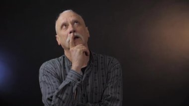 Stüdyodaki düşünceli Avrupalı olgun adam karanlık arka planda izole edilmiş.