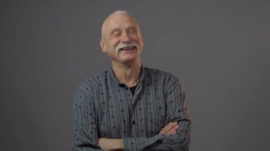 Stüdyodaki gülümseyen Avrupalı olgun adam karanlık arka planda izole edilmiş.