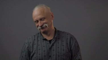 Stüdyodaki gülümseyen Avrupalı olgun adam karanlık arka planda izole edilmiş.