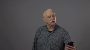 Avrupalı olgun bir adam karanlık arka planda izole edilmiş bir şekilde stüdyoda selfie çekiyor.