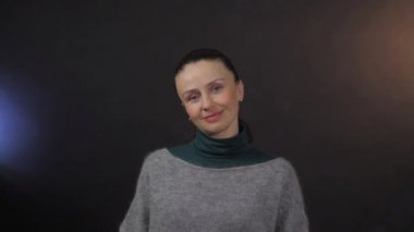 Stüdyodaki mutlu Avrupalı yetişkin kadın karanlık arka planda izole edilmiş.