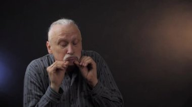 Avrupalı olgun bir adam stüdyoda koyu arka planda izole edilmiş bıyıklara dokunuyor