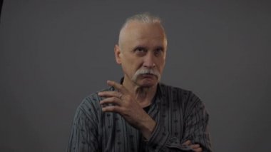 Stüdyodaki düşünceli Avrupalı olgun adam karanlık arka planda izole edilmiş.