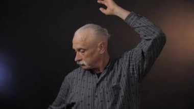 Stüdyoda dans eden Avrupalı olgun bir adam karanlık arka planda yalnız.