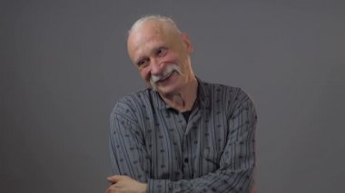 Stüdyodaki gülümseyen Avrupalı olgun adam karanlık arka planda izole edilmiş.