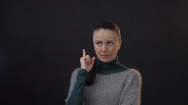 Stüdyodaki düşünceli Avrupalı yetişkin kadın karanlık arka planda izole edilmiş.
