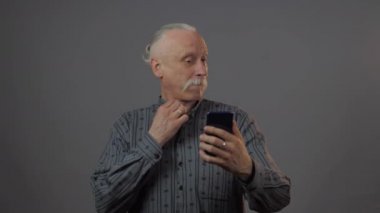 Avrupalı olgun bir adam karanlık arka planda izole edilmiş bir şekilde stüdyoda selfie çekiyor.