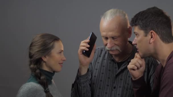 사람들은 어두운 배경에 고립되어 스마트폰을 듣는다 — 비디오