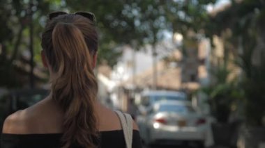 Avrupalı bir kız Sri Lanka 'da sessiz bir caddede yürüyor, ağır çekimde. Kasaba çevresindeki turizm kavramı